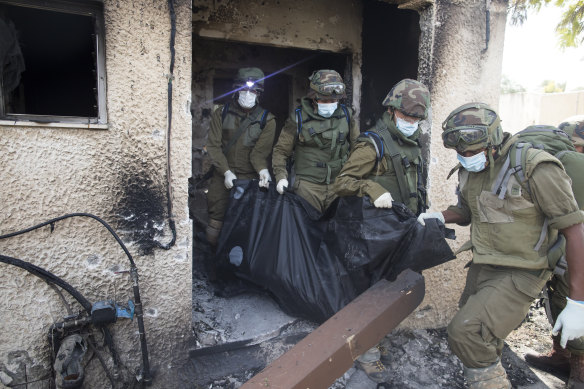 Israeli soldiers remove the body of civilian, who was killed days earlier in an attack by Palestinian militants on this kibbutz near the border with Gaza.